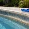Calcium scale along pool waterline tile with cleaning tools nearby