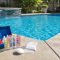 Pool water stabilizer CYA test kit beside a clear swimming pool