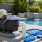 Pool pump equipment pad with clear pump lid and swimming pool in background