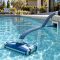 Suction pool cleaner hose and flow gauge being checked beside a clear backyard pool