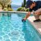 Pool professional photographing an anti-entrapment main drain cover from the deck of a clear backyard pool