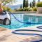 Robotic pool cleaner being lifted by its handle with a relaxed untwisted blue cable beside a backyard pool